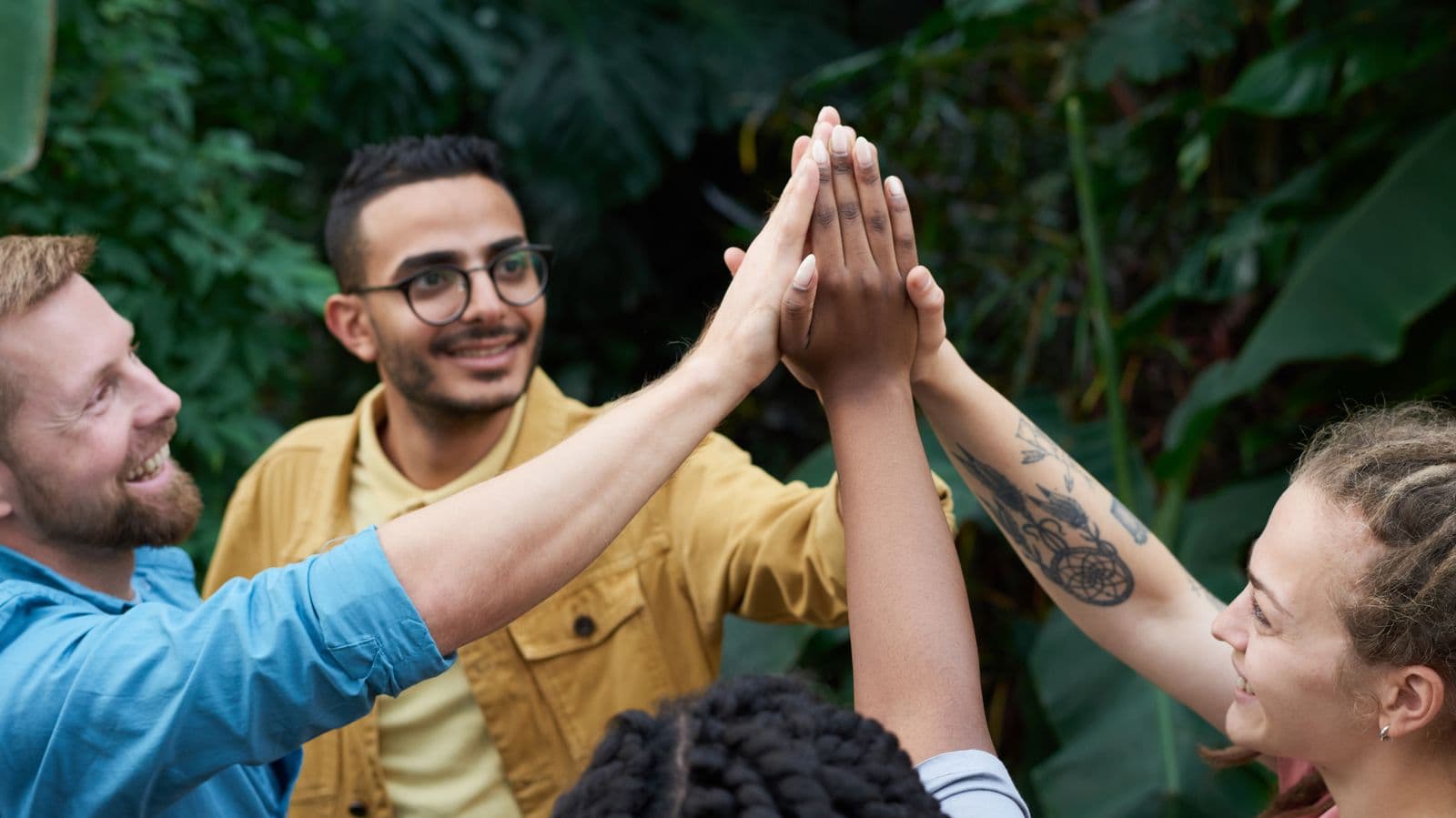 Grupo de personas chocando las manos en un entorno natural, transmitiendo apoyo y comunidad